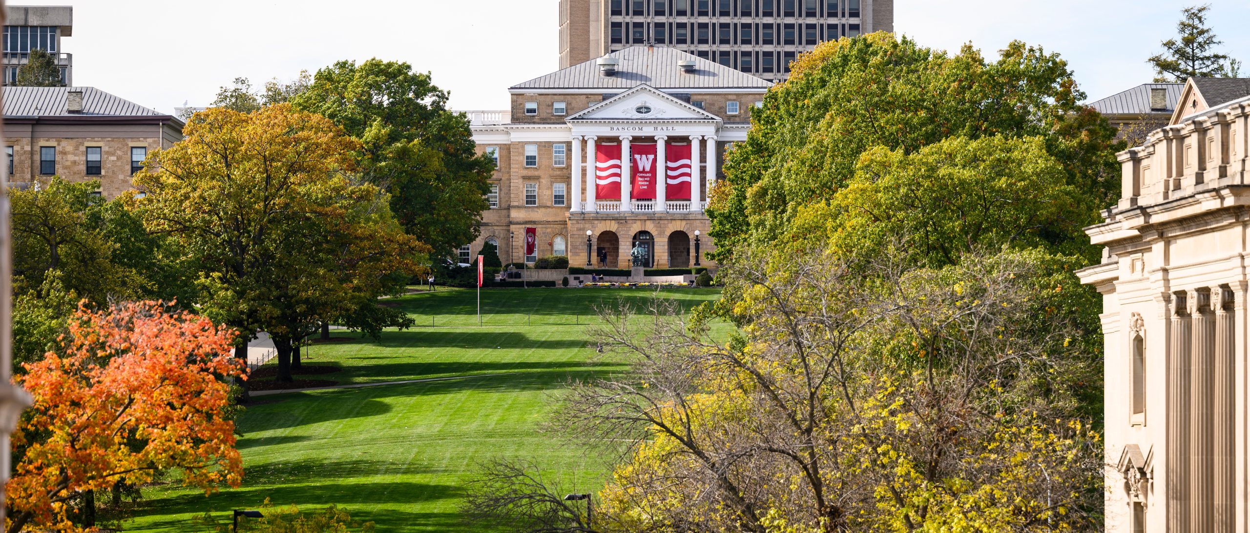 Basom Hill is flanked by trees changing colors with Bascom Hall showing the “W” banners “Forward has no finish line” with Van Hise Hall rising in the background during an autumn day on the University of Wisconsin-Madison campus on Oct. 27, 2021.