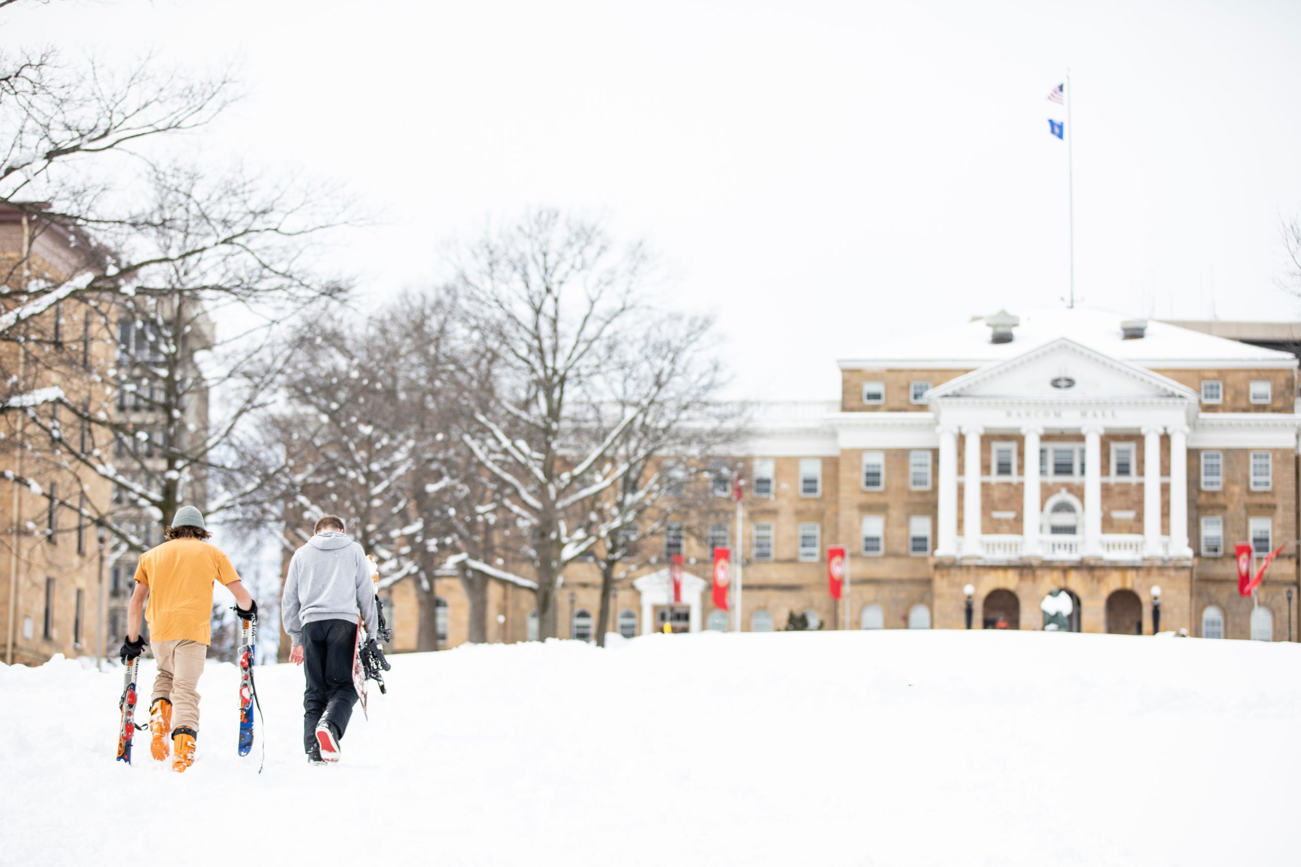 Two people walking in the snow in front of Bascom Hall