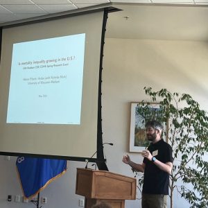 A person standing behind a podium and presenting with a screen behind them.