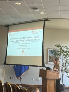 A person standing behind a podium and presenting with a screen behind them.